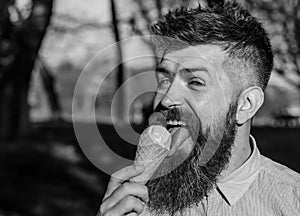 Man with long beard licks ice cream, close up. Bearded man with ice cream cone. Man with beard and mustache on happy