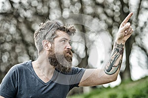 Man with long beard and mustache pointing upwards with finger, defocused background. Guy looks cool with stylish beard