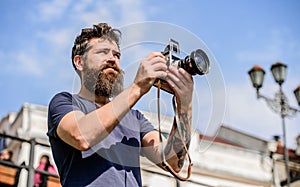 Man with long beard shooting photos. Manual settings. Photographer hold vintage camera. Modern blogger. Content creator