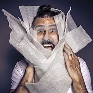 Man with long hair and beard screams wrapped in plastic packaging