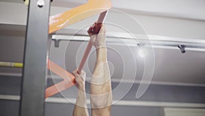 Man with long hair makes pull-ups on the turnstile