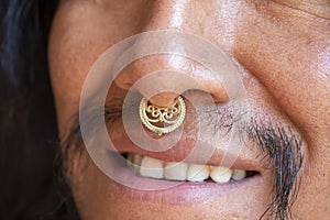 Man with long hair wearing a metal septum piercing at his nose