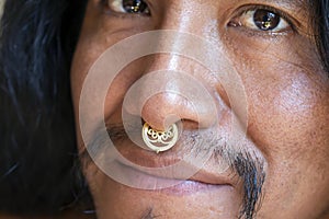 Man with long hair wearing a metal septum piercing at his nose