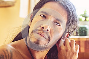 Man with long hair wearing a metal septum piercing at his nose