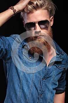 Man with long red beard wearing sunglasses, fixing his hair