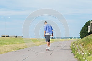 Man with longboard or skateboard riding on road