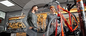 Man look at colleague look at bicycle in workshop