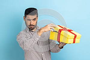 Man look inside gift box, unpacking present to know what he received, frustrated with content.