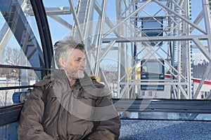 The man looking afar from a ferris wheel cabin