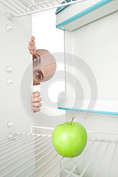 Man looking at apple in fridge