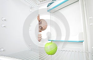 Man looking at apple in fridge