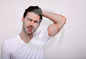 Man looking away and keeping hands behind head while standing against gray background