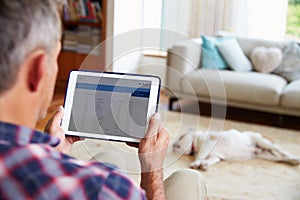 Man Looking At Banking App On Digital Tablet