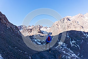 A man looking at the beautiful panorama of  mountain peaks and blue sky, after hiking to the Toubkal mountain in Morocco