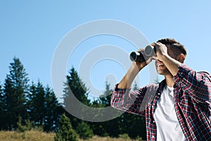 Man looking through binoculars outdoors on sunny day