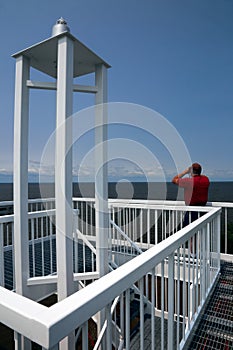 Man Looking Through Binoculars at Top of Harbor Light