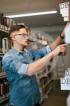 Man Looking For Book In Bookstore. Student In Library