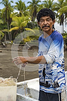 Man looking at the camera preparing his net for fishing
