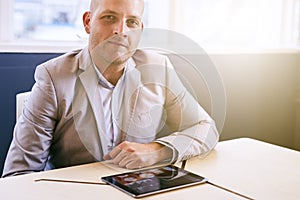 Man looking at camera with tablet in front of him