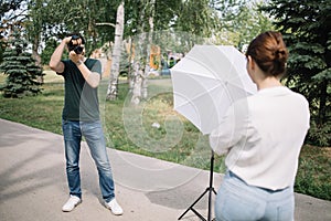Man looking through camera viewfinder and making outdoor photo session