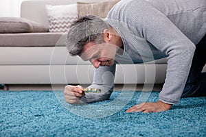 Man Looking At Carpet Through Magnifying Glass