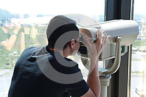 Man looking through a coin operated Tower Viewer or Stationary Binoculars