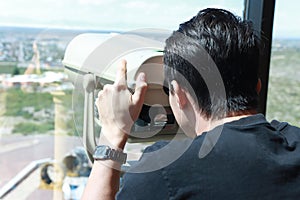 Man looking through a coin operated Tower Viewer or Stationary Binoculars