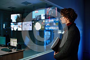 Man looking at computer screen reflection in server room window