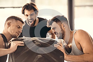 man looking at concentrated sportsmen lifting tire