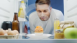 man looking at delicious cupcake near