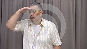 Man looking into distance, hand protecting from sun. White Background.