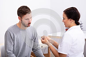 Man Looking At Doctor Holding Hearing Aid