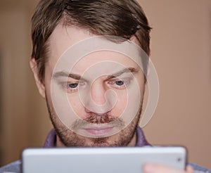 Man looking down at pda on beige background