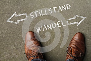 Man looking down at the words Stillstand and Wandel (stagnancy change in German) photo