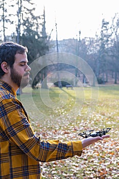 Man looking a drone perched on his hand with a park in background