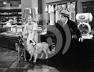 Man looking fearful at two dogs in a butcher store photo