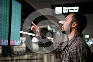 Man is looking at flight arrivals and departures board at airport