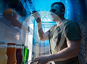 Man looking in a fridge for something to snack on