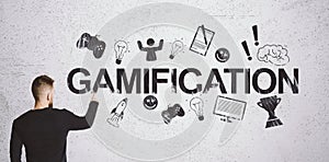 Man looking on gamification text and gaming icons on wall