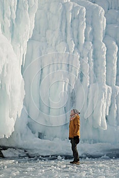 Man Looking on a Giant Icicles on a Frozen Coast Lake Baikal, Russia