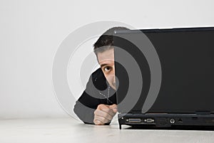 Man looking and hiding behind laptop