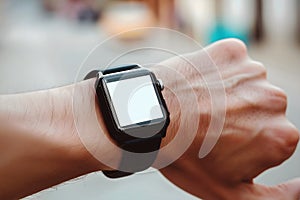 Man looking at his blank empty white smart watch screen on his wrist, technology accessories concept background