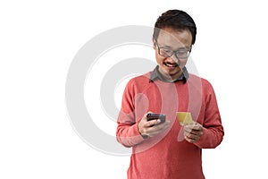 A man looking at his credit card and smartphone. e commerce and payment concpt image isolated in white background with photo