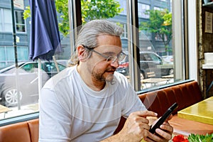 Man looking at his hands with smartphone texting message or dialing