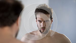 Man looking at his mirror reflection with hatred and shame, feeling guilty