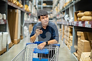 Man looking at his mobile phone and shopping in warehouse store