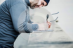 Man looking at his notebook and writing something - close up shot