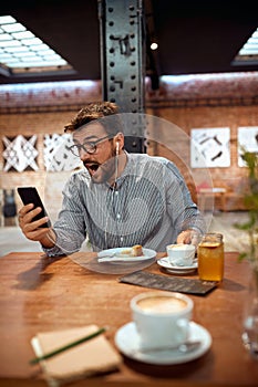 man looking at his phone and making a suprise face excpression