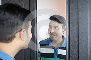 A man looking at his reflection in mirror smiling in happy mood