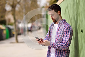 Man looking his smart phone in urban background. Guy wearing casual clothes. Lifestyle concept